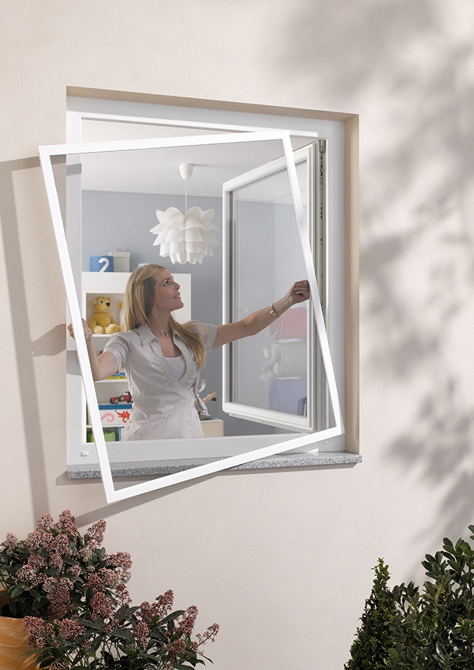 Wohn-Profis Frau montiert Spannrahmen als Insektenschutz am Fenster